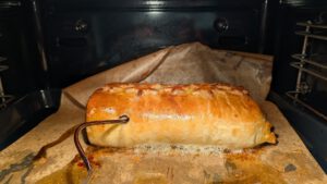 Beef Wellington en cours de cuisson au four, avec le câble d'une sonde thermomètre