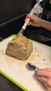 Une main badigeonne le filet saisi de moutarde sur une planche à bord vert