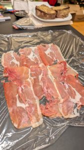 Tranches de jambon de Parme qui se chevauchent sur une feuille de film alimentaire