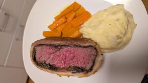 Tranche de Beef Wellington dressée avec de la purée et des carottes glacées