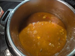 Sauce du goulash orange-brun avec champignons et morceaux de poivron qui frémit dans la cuve en inox d'un Instant Pot