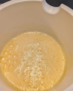 Mélange jaune pâle d'œufs et de sucre fouettés, avec de fines bulles, dans un saladier blanc