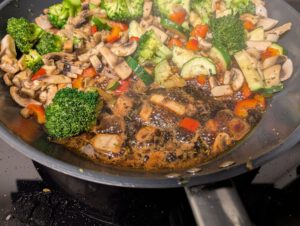 Gros plan sur la réduction de vinaigre balsamique sombre qui bouillonne dans la poêle à côté des légumes