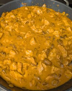 Poêle de sauce stroganoff crémeuse orange au paprika avec des morceaux de poulet et des champignons